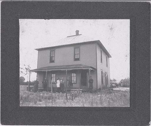 Unlabeled photo.  Notice person exiting outhouse.